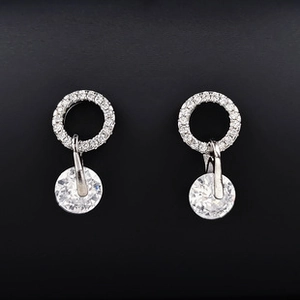 Détail des boucles d'oreilles goutte d'eau avec cristaux ronds étincelants sur fond noir mat