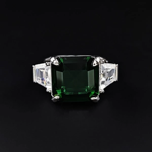 Classic silver ring with emerald cut green stone and trapezoid side diamonds