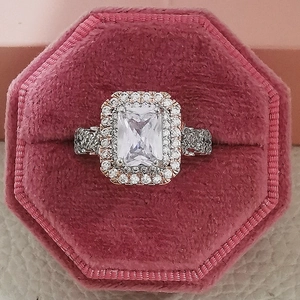Elegant princess cut diamond ring with halo and pavé band in a pink velvet box