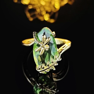 Luxurious dragonfly ring with olive green marquise gemstone on a gold band background