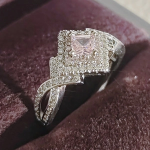 Macro view of pink square crystal ring with double halo and crisscross band in jewelry box