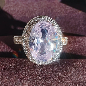 Macro shot of an elegant halo ring featuring a large oval pink gemstone and silver metal