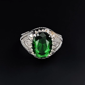 Close-up of vintage emerald cut green gemstone ring with detailed silver engraving