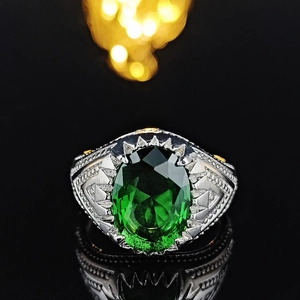 Macro shot of vintage silver ring with oval emerald gemstone and gold geometric accents