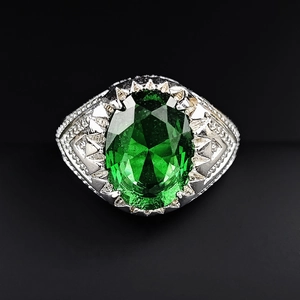 Macro shot of silver ring featuring oval emerald gemstone and sparkling halo detail