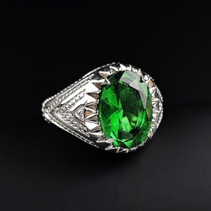 Close-up of vintage emerald green gemstone ring with detailed geometric silver engraving