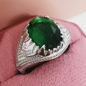 Macro detail of vintage emerald cocktail ring with intricate silver floral engraving
