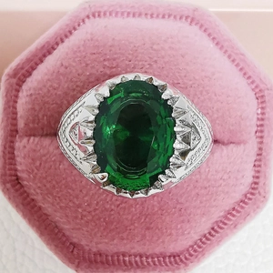 Close-up of vintage emerald ring with green stone in a pink velvet jewelry box