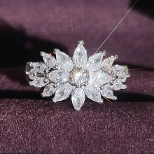 Makro-Detail des silbernen Blumenrings mit Marquise-Schliff auf lila Samthintergrund