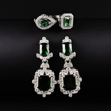 Close-up of luxury silver jewelry set with emerald green stones and diamond accents