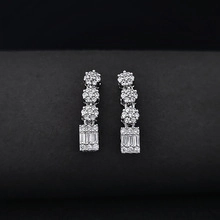 Macro detail of silver drop earrings featuring tiered clusters of sparkling round and square stones