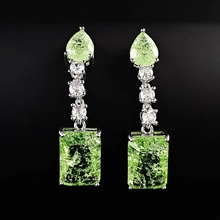 Detailed macro of silver drop earrings with emerald cut green gemstones and zircon beads