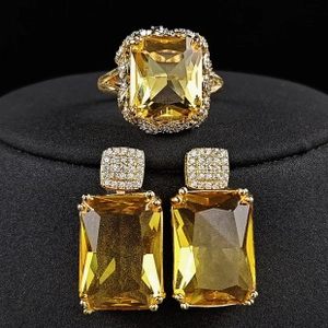 Detail view of emerald cut yellow gemstone jewelry set with halo stones on black velvet