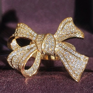 Macro shot of gold bow ring with pavé-set sparkling zircons on purple velvet