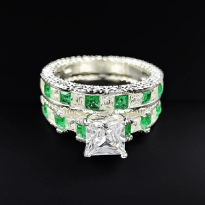 Detail of silver bridal ring set with princess cut zircon and green emerald accents