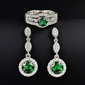 Classic emerald jewelry set with silver ring and drop earrings on black background