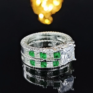 Close-up of 925 silver ring set with princess cut square zircon and green gemstones