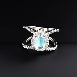 Macro detail of pear-shaped blue gemstone ring with crisscross pavé band and silver finish
