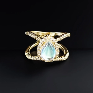 Macro detail of rose gold teardrop ring with blue-green moonstone and pavé diamond band