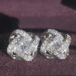 Boucles d'oreilles nœud argentées avec zircon central sur présentoir à bijoux