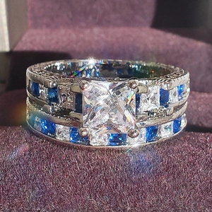 Detailed macro view of silver ring with princess cut clear stone and blue side gems