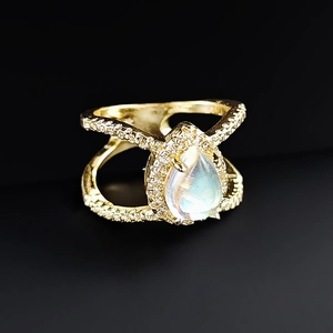 Macro view of pear shaped moonstone ring in rose gold with pavé diamonds and X-split band