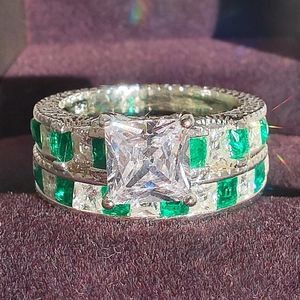 Macro detail of luxury silver ring with emerald-cut zirconia and green side stones