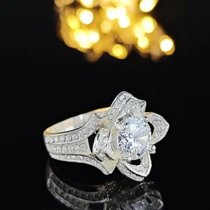 Macro side view of elegant silver flower ring with zircon stones and warm bokeh reflection