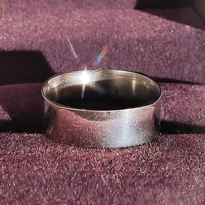 Vista macro di un anello largo in metallo argento lucido su scatola di velluto
