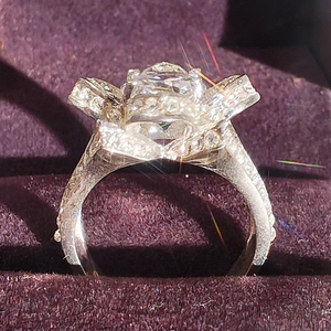 Macro shot of luxury zircon rose ring with diamond accents in purple velvet box