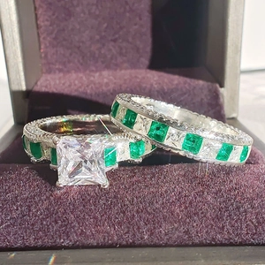 Luxurious silver square zircon ring set with green emerald accents in a purple velvet box