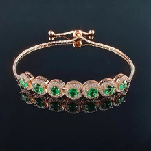 Detail view of gold adjustable slider bracelet with seven green gems and pavé crystals