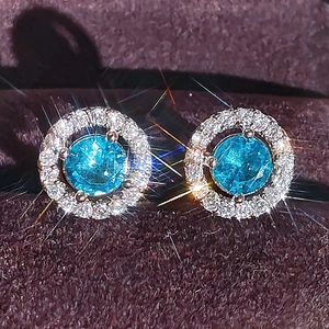 Classic round halo stud earrings with blue gemstones and white diamonds in a gift box