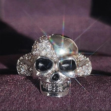 Detailed view of silver skull ring with pavé rhinestones on purple velvet background