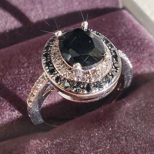 Elegant oval black zircon halo ring with white diamond accents on purple velvet