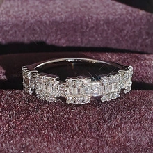 Macro view of silver stainless steel ring with pavé-set rectangular stones in purple box