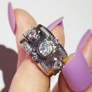 Close-up of a wide two-tone band ring featuring a large round zircon center stone on a finger