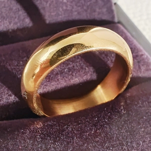 Polished gold stainless steel minimalist band ring displayed in a purple velvet jewelry box