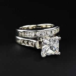 Detail eines Brautring-Sets mit Prinzess-Schliff und Zirkonia auf schwarzem Grund