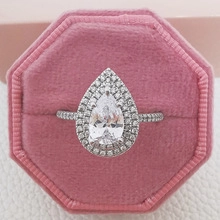 Detailed macro view of pear-cut sparkling engagement ring in a pink velvet jewelry box
