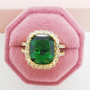 Elegant gold plated ring with emerald cut green gemstone in a pink velvet jewelry box