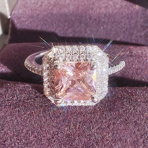 Luxurious halo ring featuring a princess-cut pink gemstone and double pave diamond bands