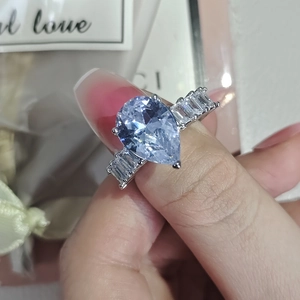 Detailed macro view of pear-shaped light blue gemstone ring with tapered baguette diamonds