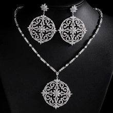Detail view of ornate silver baroque jewelry set with circular hollow pendant and earrings