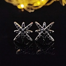 Macro shot of silver starburst earrings featuring pavé black cubic zirconia on a dark surface