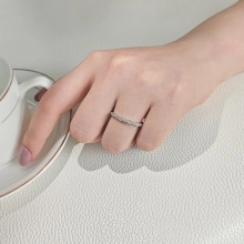 Detail of silver braided ring with micro-pave stones worn on hand with coffee cup
