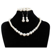 Detail of white faux pearl jewelry set with sparkling rhinestone spacers on black bust