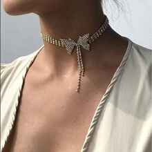 Detailed close-up of a silver bow choker necklace with rhinestones and fringe tassels