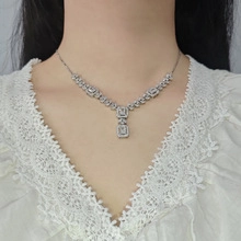 Detailed view of silver necklace with rectangular and round clear crystals on model