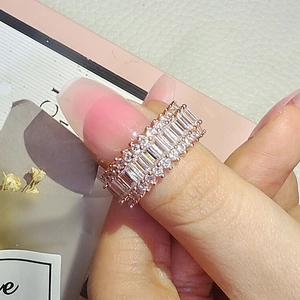 Nahaufnahme eines roségoldenen Breitbandrings mit Smaragdschliff und Pavé-Diamanten